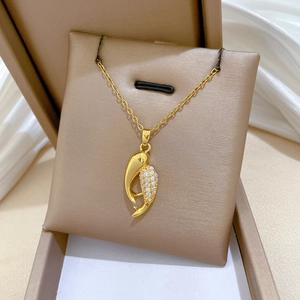 Gros plan du pendentif poisson en or avec zircons sur un fond en soie blanche