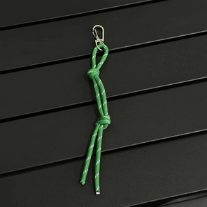 Detail of green nylon braided rope charm with reflective silk and silver metal carabiner