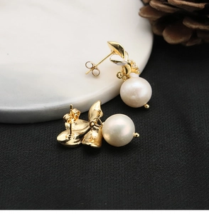 Macro view of gold flower pearl earrings with zircon stones on marble and black surface