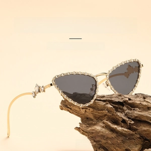 Detailed view of cat eye sunglasses with rhinestones and metal star on wood base