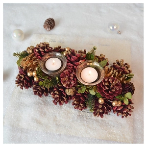 Close-up of vintage pine cone candle holders with burgundy accents and golden beads