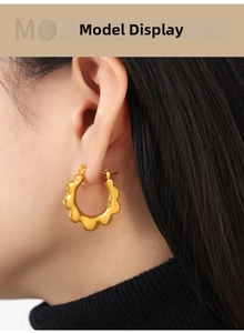 Detail view of gold-plated titanium steel hoop earrings with elegant wavy sun-edge texture