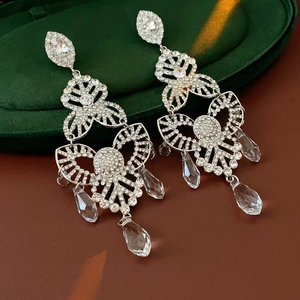 Macro shot of silver crystal flower drop earrings on a green velvet jewelry box