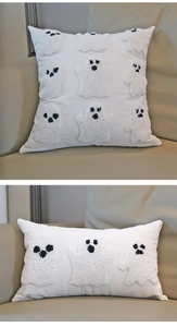 Detail of cream festive pillow covers featuring white bouclé ghost embroidery on sofa