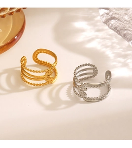 Détail de bagues ouvertes en or 18 carats et argent avec motifs perlés sur surface en verre