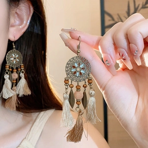 Detail of bohemian dreamcatcher earrings with cream tassels and bronze feather charms