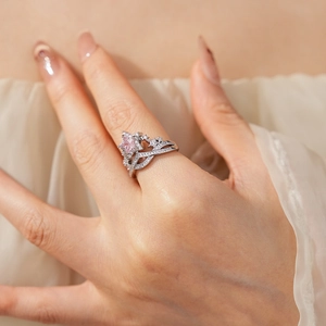 Detail of star crown ring with pink zircon on model hand against soft fabric background
