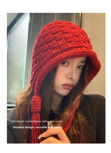 Detail of red knitted balaclava with long braided tassels for winter warmth