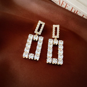 Detail shot of sparkling cubic zirconia square dangle earrings on dark silk fabric