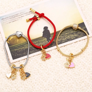 Trois bracelets avec breloques cœur plaqués or 18k en corde rouge et maille serpent