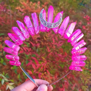 Detail of pink crystal wicca crown with silver crescent moon held against red foliage