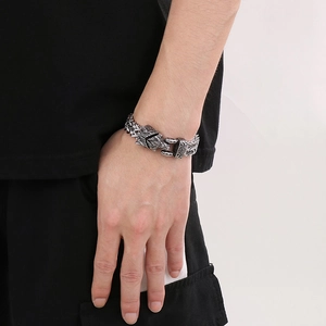 Detail of masculine stainless steel braided chain bracelet with a wolf head clasp on wrist