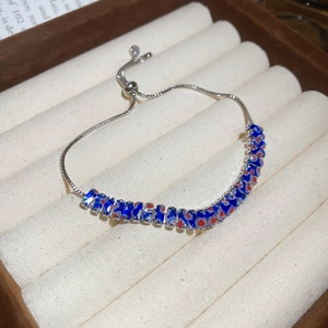 Gros plan du bracelet argenté ajustable avec breloques en émail bleu et motifs floraux rouges