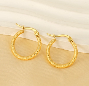 Detailed close-up of gold-plated hoop earrings with twisted spiral texture on satin