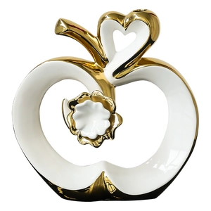 Modern ceramic apple statue in white and gold with a cutout heart and floral detail
