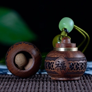 Close-up of a carved wooden aroma pendant with brass details and a lucky character