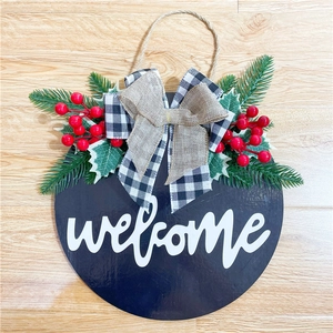 Close-up of wooden welcome sign with buffalo plaid bow and red berries for Christmas decor