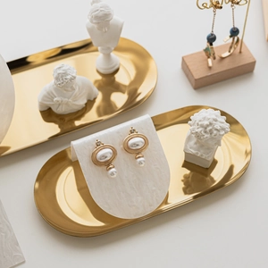 Vintage gold alloy earrings with white pearls on a minimalist white textured display