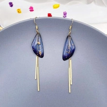 Detailed view of butterfly wings tassel earrings with gold foil in blue resin