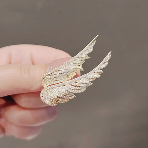 Close-up of a golden wing brooch with micro-pave crystals showing intricate metal details