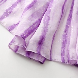 Detail of purple tie-dye gauze fabric with shimmering gold glitter and soft texture