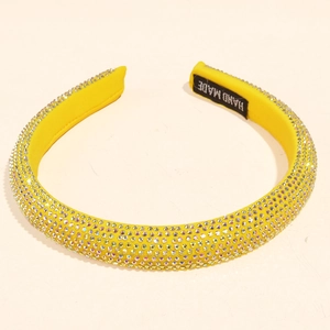 Close-up of bright yellow rhinestone headband featuring a handmade label on the inner side