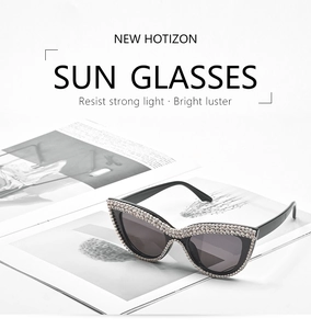 Detail of cat eye sunglasses with silver rhinestones on black frames and dark grey lenses