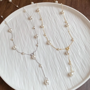 Detailed shot of long Y-shaped faux pearl necklaces in gold and silver finishes
