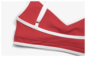 Macro shot of red sports bra showing contrast white piping and metallic ring detail