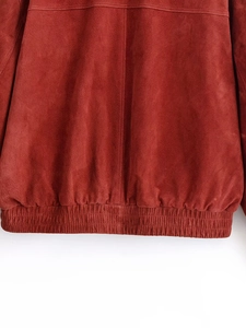 Détail de la veste en daim marron rouge montrant l'ourlet élastique et les coutures droites