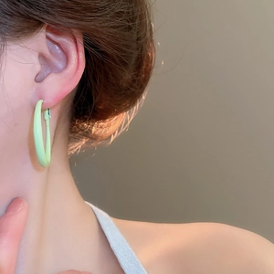 Close-up of a model wearing a light green minimalist hoop earring with a glossy finish