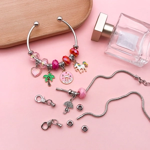 DIY jewelry making kit featuring pink crystal beads and silver charms on a tray