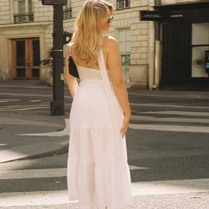 Outdoor shot of a tiered white ruffle skirt paired with a beige backless halter top