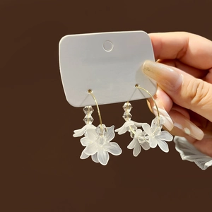 Elegant gold hoop earrings with white matte petals and clear faceted bead tassels