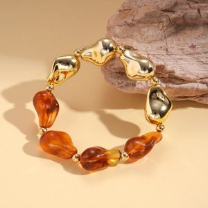 Detailed macro view of irregular gold metal and amber resin beads on a minimalist bracelet