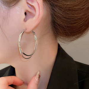 Gros plan d'un mannequin portant des boucles d'oreilles doubles anneaux géométriques