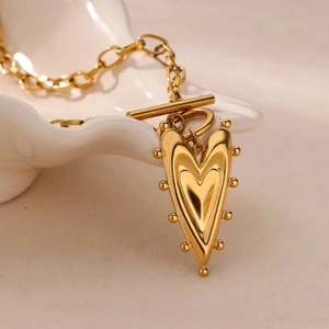 Collana a doppio strato dorata con ciondolo a cuore e chiusura a T su piatto bianco