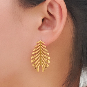 Detailed close-up of gold leaf-shaped stud earrings with intricate texture and matte finish