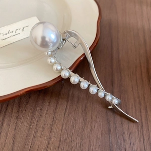 Macro view of silver alloy hair claw with S-curve design and elegant pearl tassels