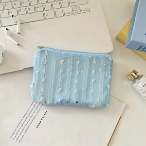 Detailed view of light blue mesh coin purse with sequins and lace on a white desk