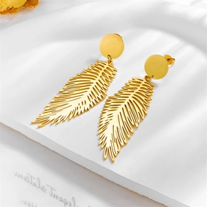 Minimalist gold feather drop earrings on white textured surface with natural light