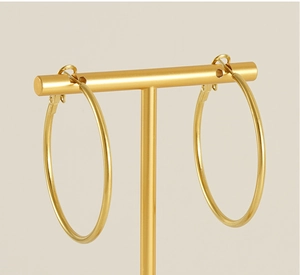 Detail view of large 18K gold plated hoop earrings on a T-bar minimalist display stand