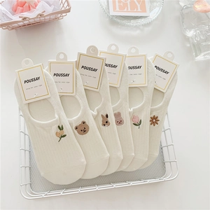 Close-up of six white cotton low cut socks with diverse animal and flower embroidery motifs
