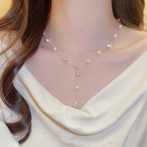 Detail of elegant Y-shaped silver necklace with white pearls and irregular metal beads