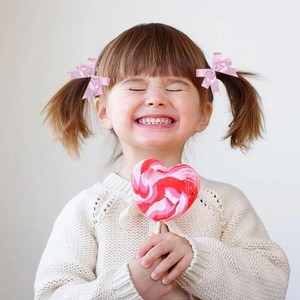 Close-up of pink bow hair accessories with reflective patterns on a young girl's pigtails
