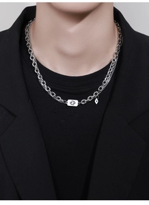 Detail of silver double-layered necklace with Cancer zodiac sign and blue evil eye pendant