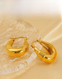 Detailed macro view of 18K gold plated oval hoop earrings with diamond-cut texture details