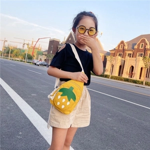 Outdoor shot of a girl wearing a yellow strawberry-shaped canvas crossbody chest bag
