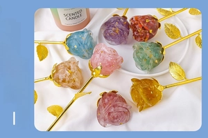 Detailed view of colorful crystal resin roses with gold foil on soft white fabric background