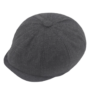 Macro detail of dark grey herringbone texture on a newsboy cap with top decorative button